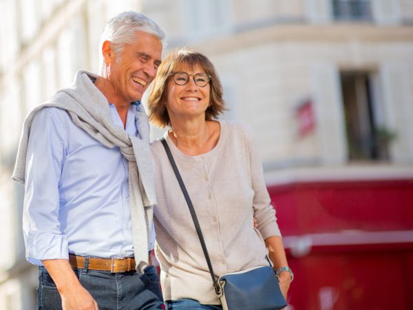 Portrait happy mature couple walking outside in city